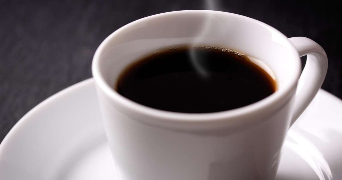 Uma xícara de café preto sem açúcar sobre uma mesa de madeira