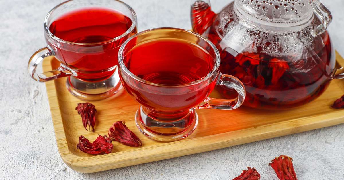Copo de chá de hibisco, uma bebida saudável e refrescante, com flores de hibisco ao fundo
