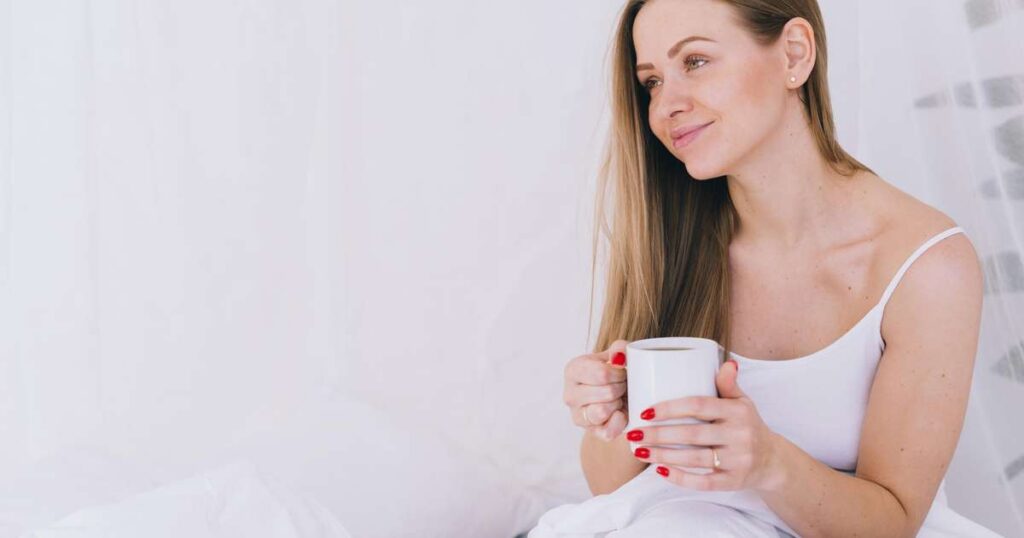 Copo de leite morno ao lado de um livro e uma vela acesa, ideal para relaxar antes de dormir