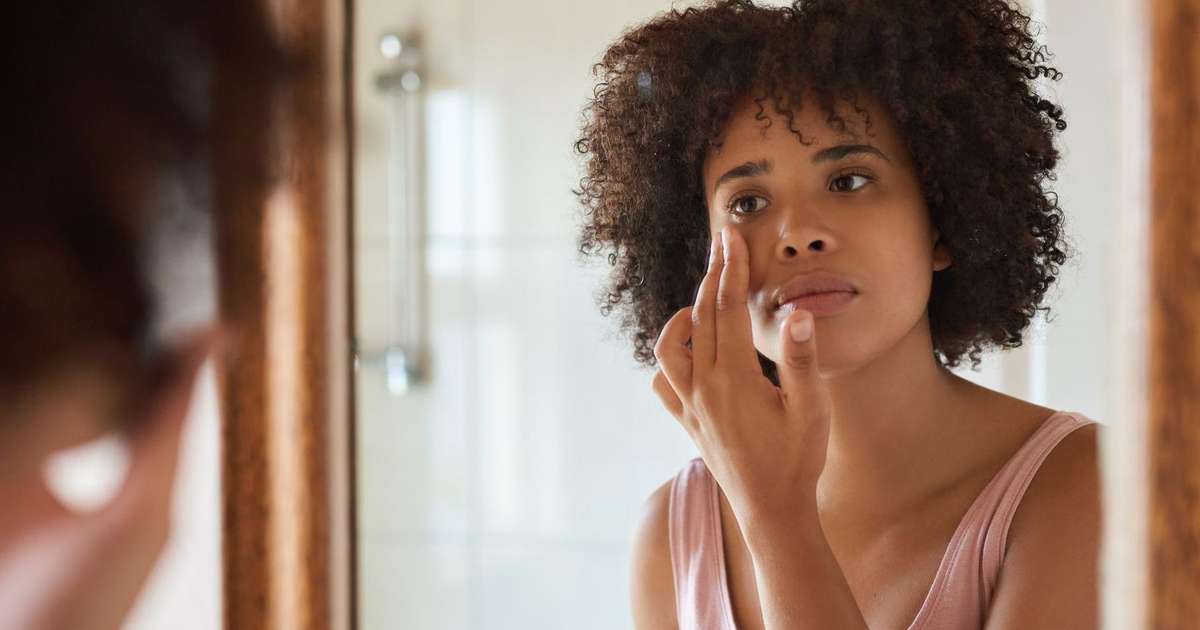 Pessoa tocando o rosto com expressão de preocupação, refletindo o impacto do estresse na pele