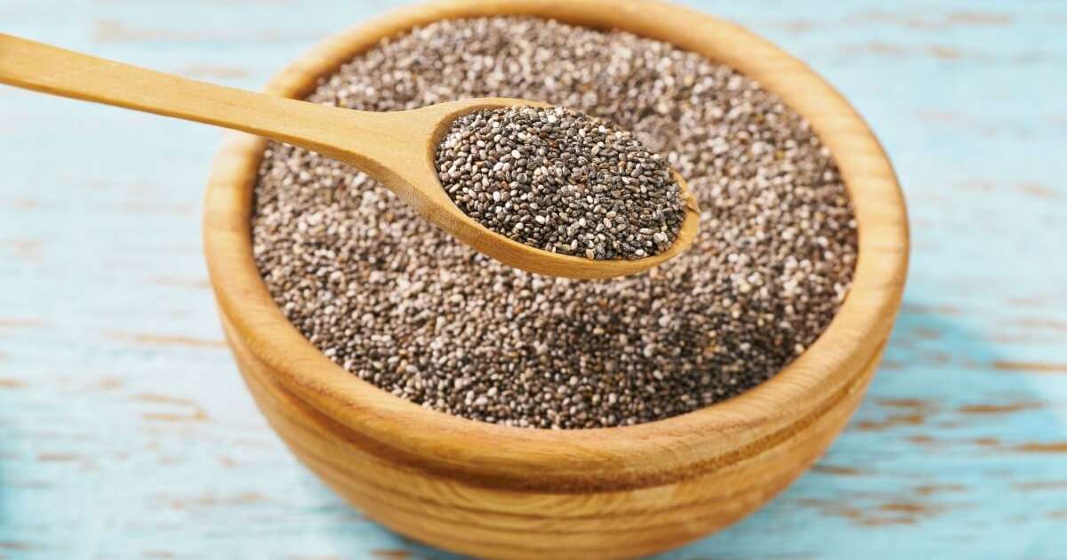 Semente de chia em uma colher com fundo de frutas e iogurte