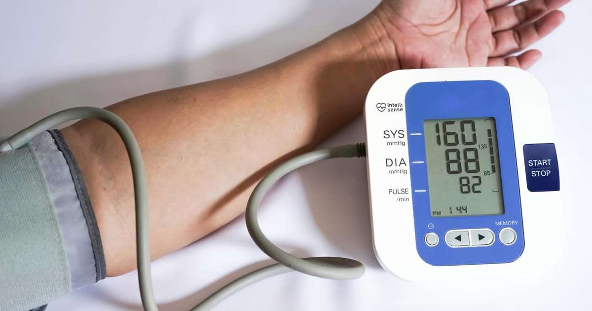 Pessoa medindo a pressão arterial com um esfigmomanômetro em casa