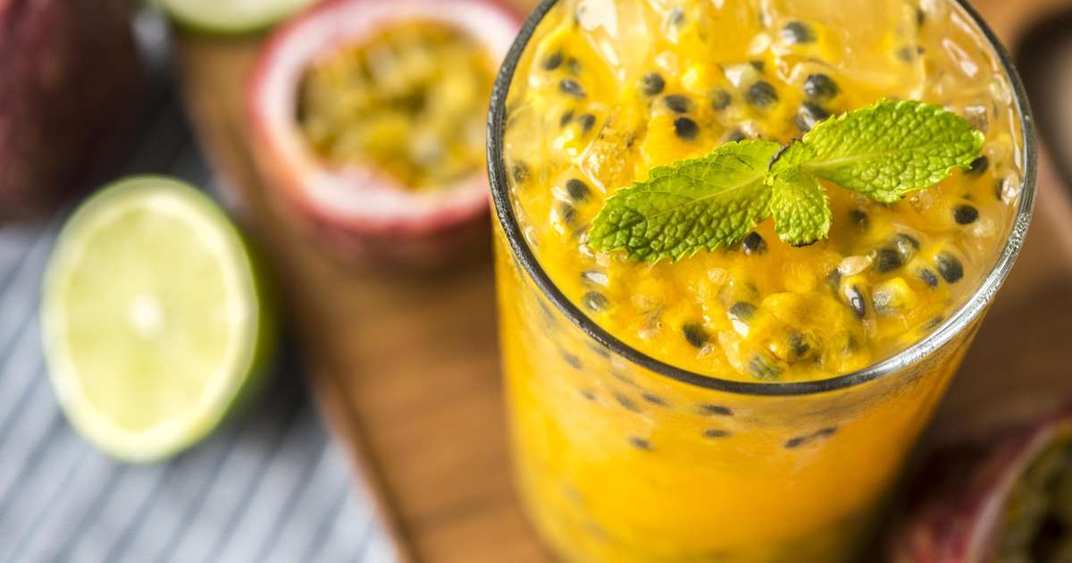 Suco natural de frutas frescas, incluindo abacaxi, limão e maracujá em um copo com gelo.