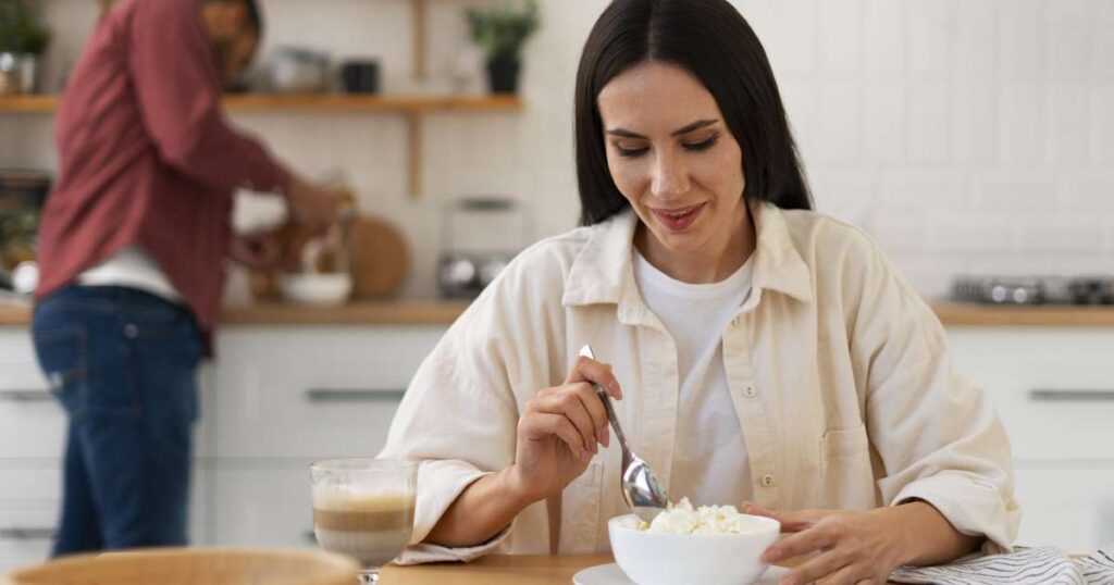 Mulher contemplando uma refeição saudável com frutas, iogurte e sementes