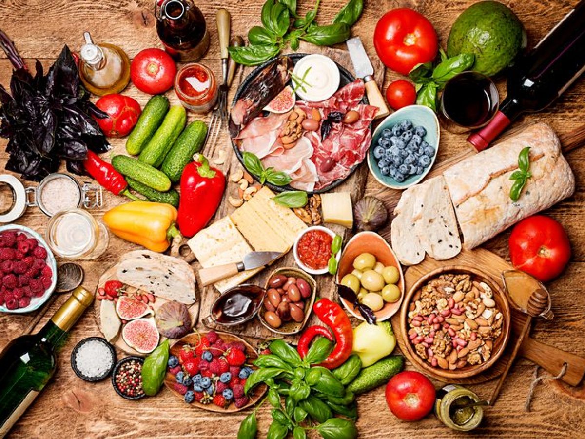 Prato colorido com ingredientes da Dieta do Mediterrâneo, incluindo frutas, vegetais, peixes e azeite de oliva.