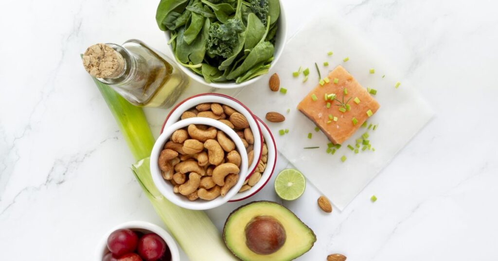 Duas tigelas com diferentes fontes de proteínas vegetais, como feijão, lentilha e grão-de-bico, em uma mesa com frutas e vegetais ao fundo.