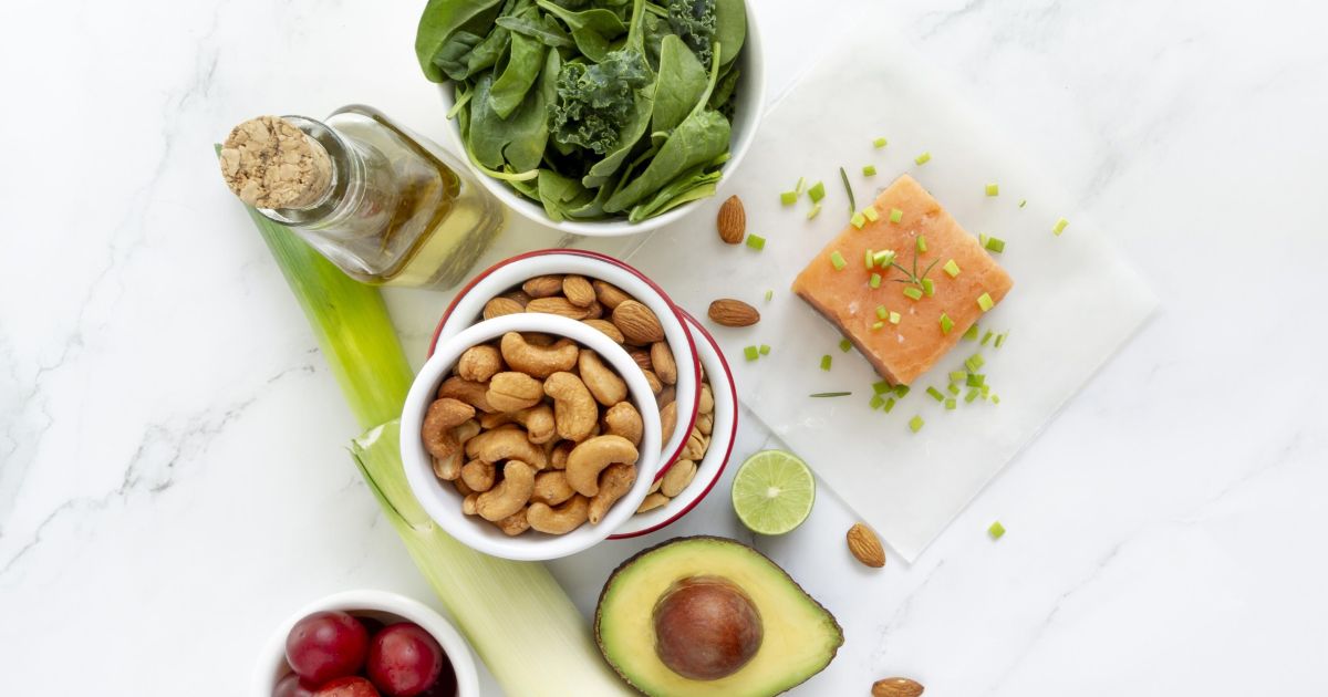 Duas tigelas com diferentes fontes de proteínas vegetais, como feijão, lentilha e grão-de-bico, em uma mesa com frutas e vegetais ao fundo.