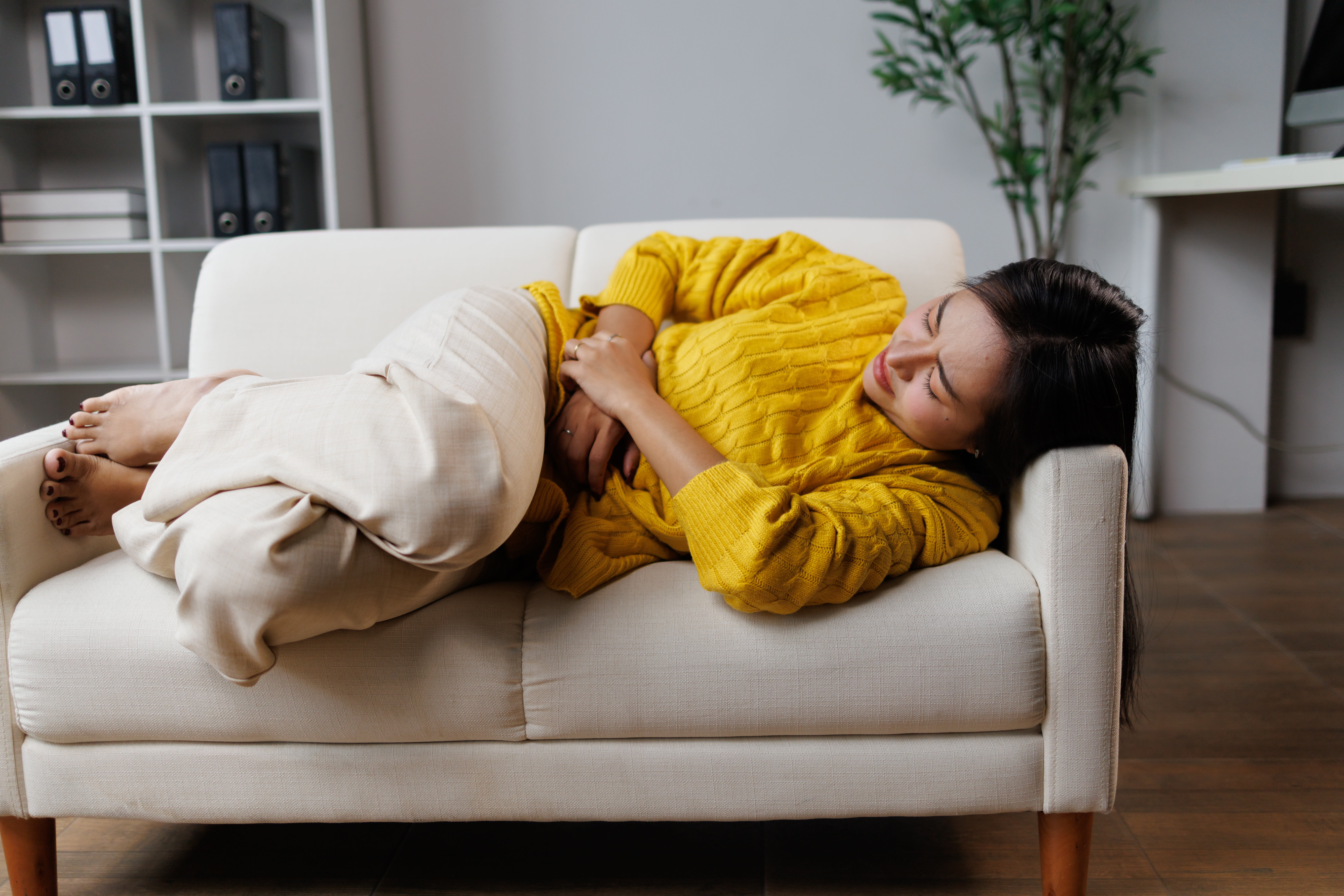 Mulher com dor abdominal durante a menstruação, sintoma que pode estar relacionado à endometriose intestinal.